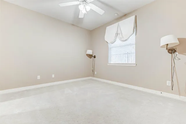 an empty room with a window and a fan
