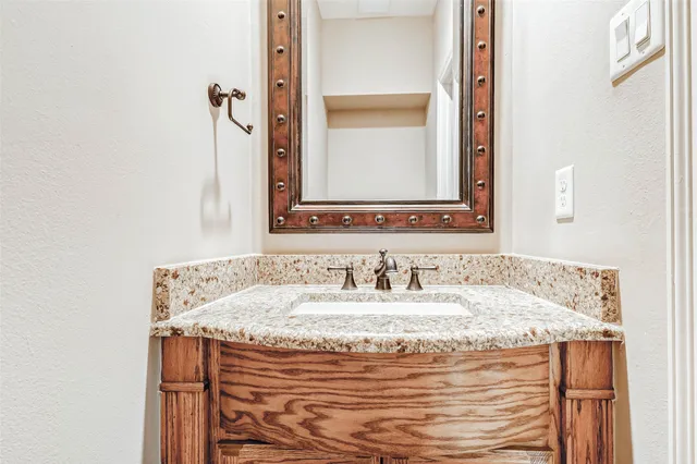a bathroom with a granite countertop sink and a mirror