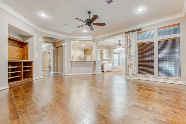 a view of an empty room with wooden floor and a window