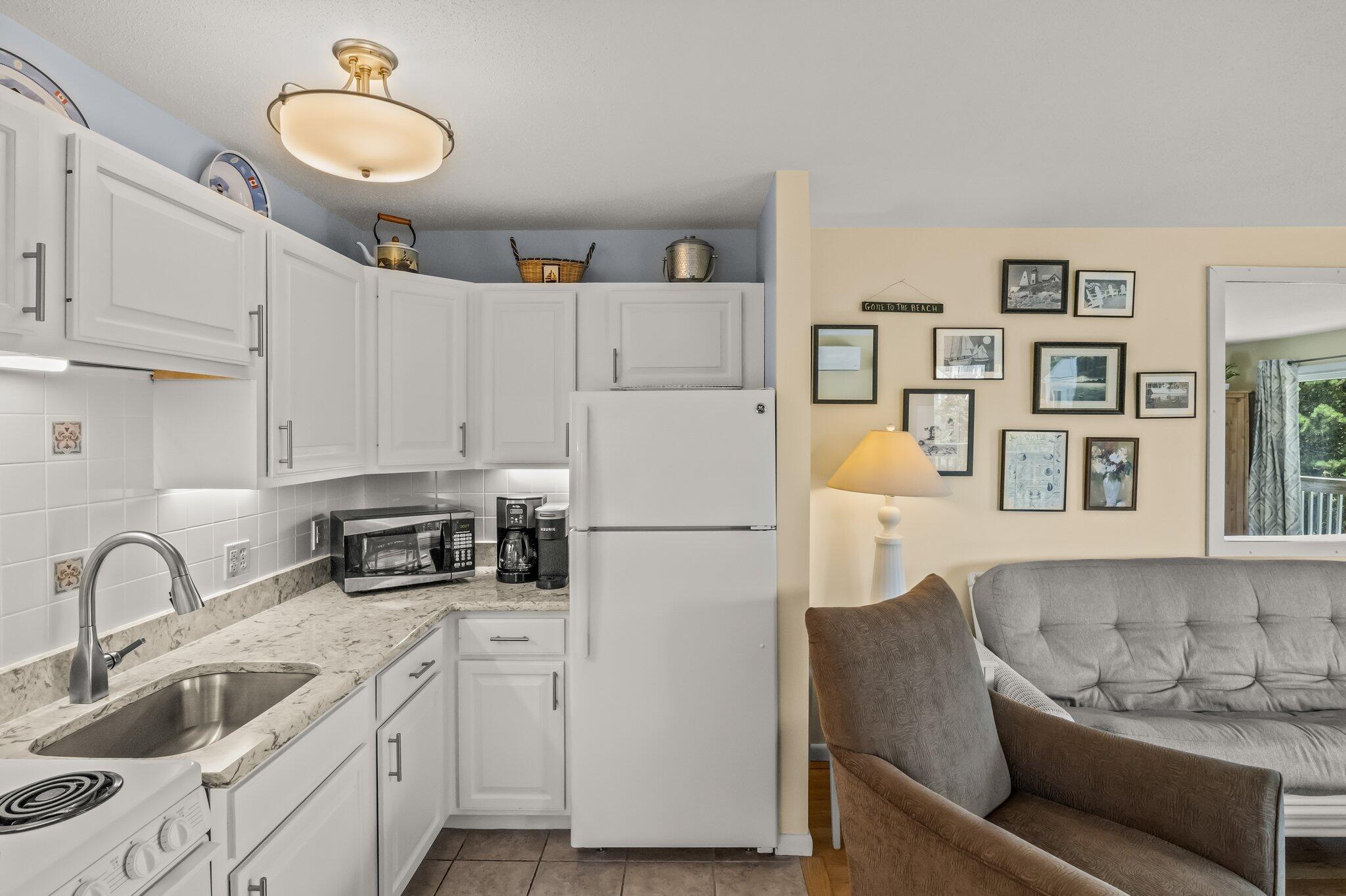 132 Shore Road, Unit 31 Truro, MA 02666 - Photo 16 of 24 a white kitchen with stainless steel appliances granite countertop a refrigerator sink and white cabinets