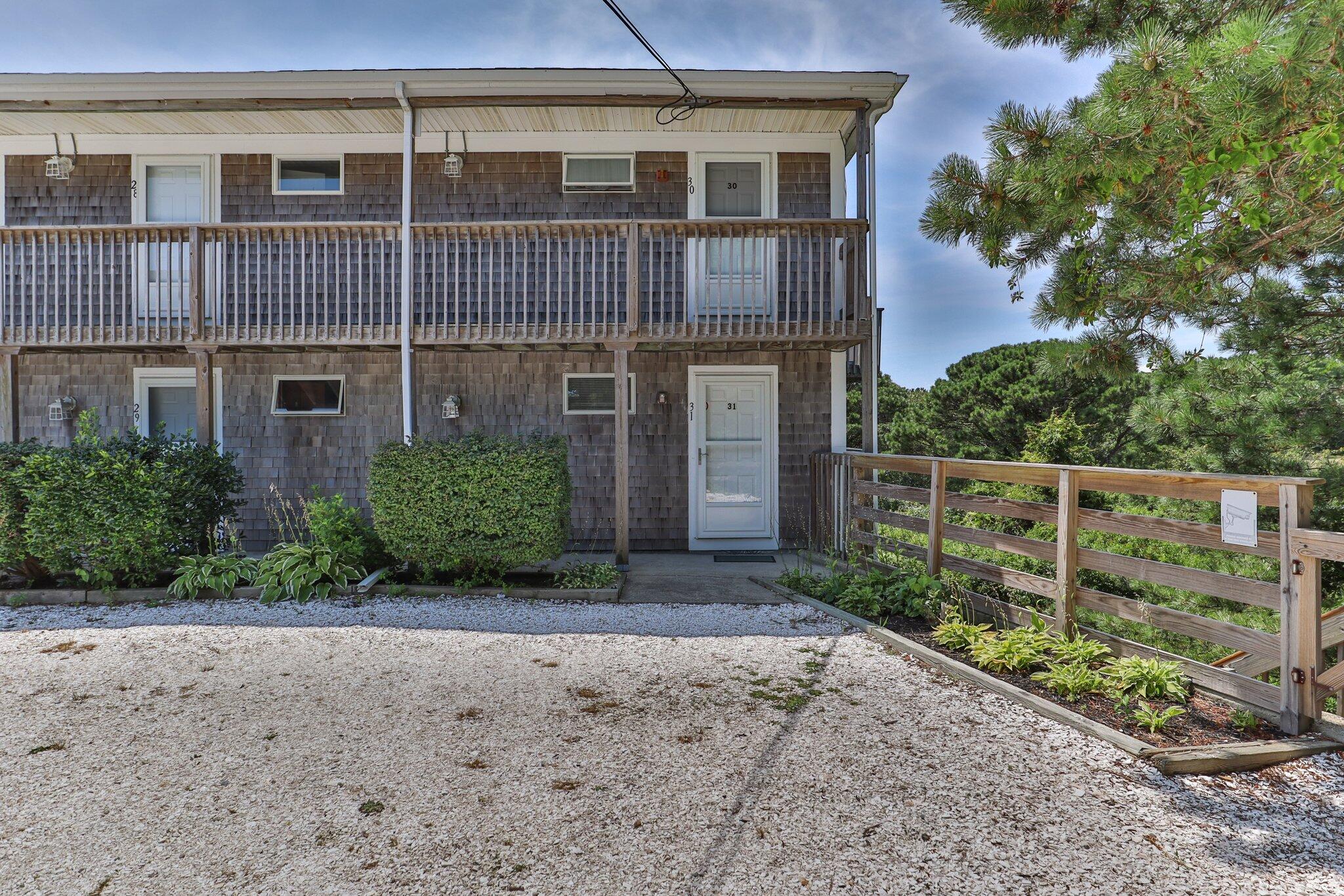 132 Shore Road, Unit 31 Truro, MA 02666 - Photo 19 of 24 a view of a brick house with large windows and a yard