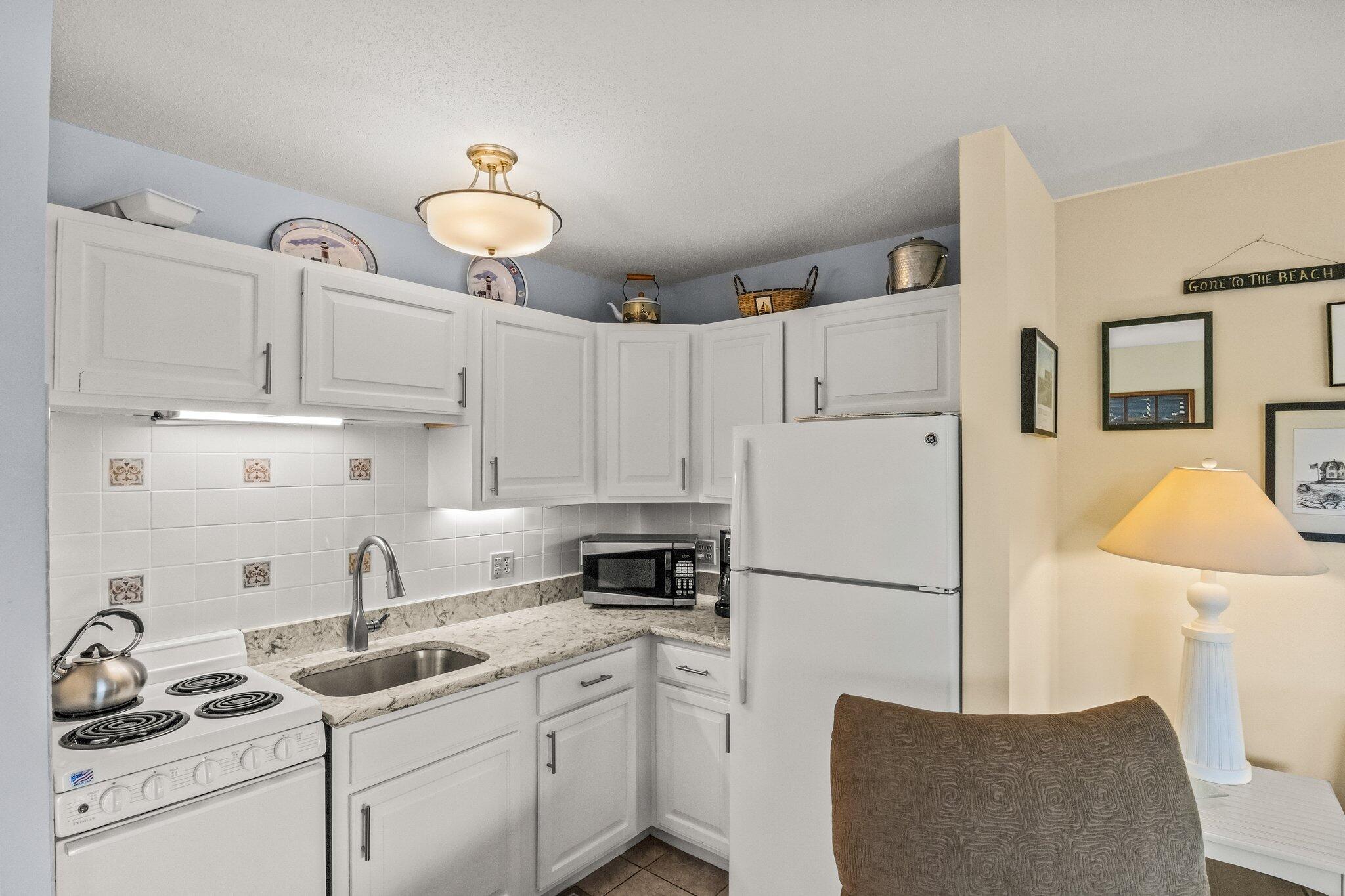 132 Shore Road, Unit 31 Truro, MA 02666 - Photo 4 of 24 a kitchen with a refrigerator a stove and white cabinets
