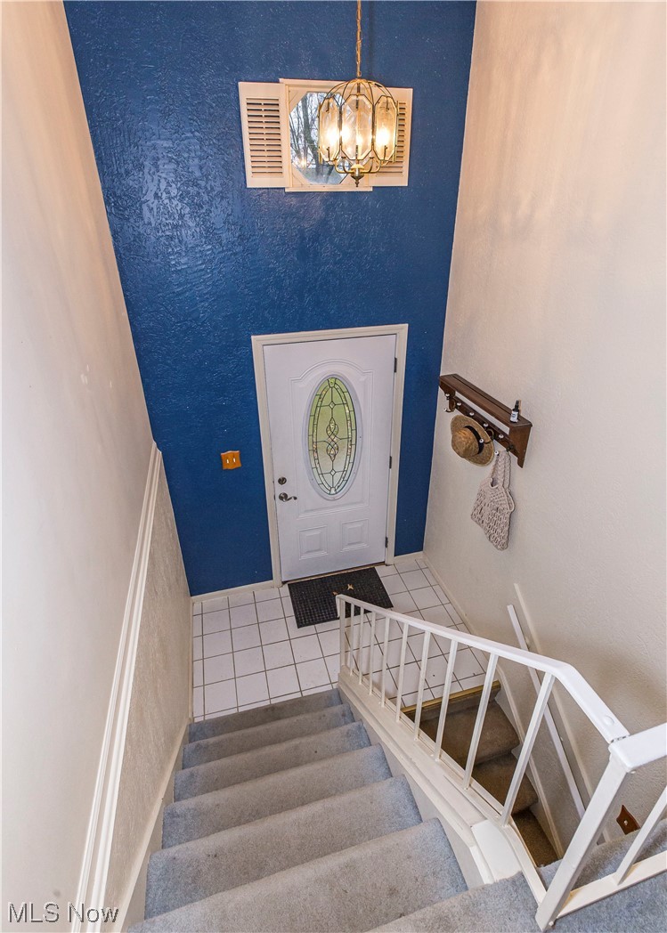 3755 North Santom Road Stow, OH 44224 - Photo 2 of 23 Staircase featuring an inviting chandelier, a high ceiling, and light tile floors
