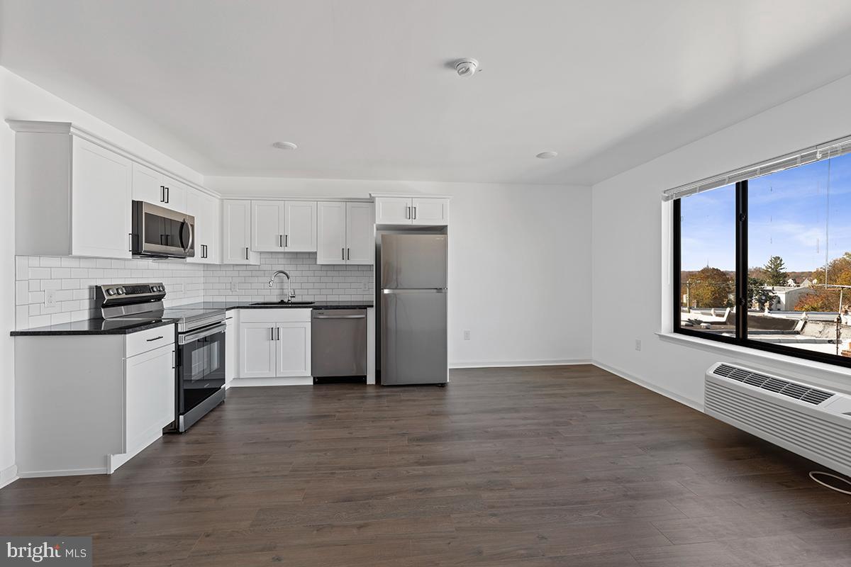 404 Fountain Street, Unit 208 Philadelphia, PA 19128 - Photo 3 of 8 a kitchen with stainless steel appliances granite countertop a stove a sink dishwasher a refrigerator and a microwave oven with white cabinets