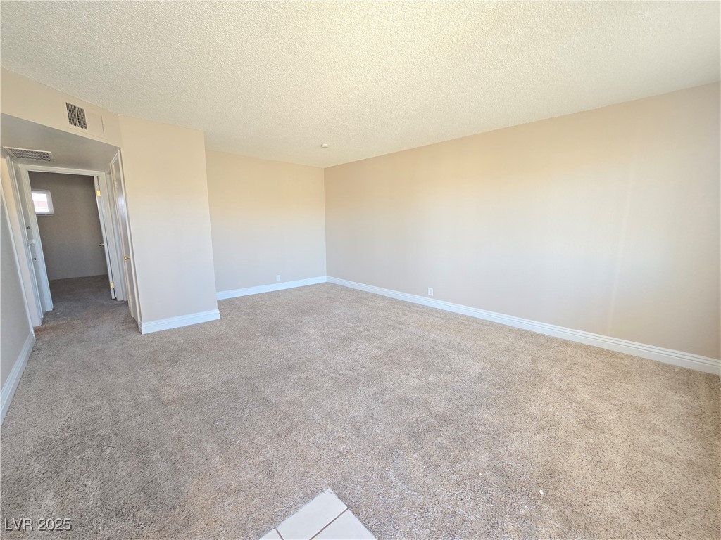 5248 Pebble Beach Boulevard, Unit D Las Vegas, NV 89108 - Photo 1 of 13 Unfurnished room with a textured ceiling and light carpet