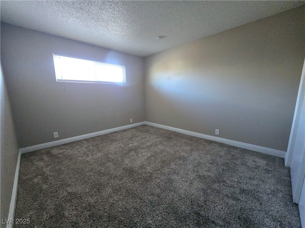 5248 Pebble Beach Boulevard, Unit D Las Vegas, NV 89108 - Photo 11 of 13 Unfurnished room featuring carpet flooring and a textured ceiling