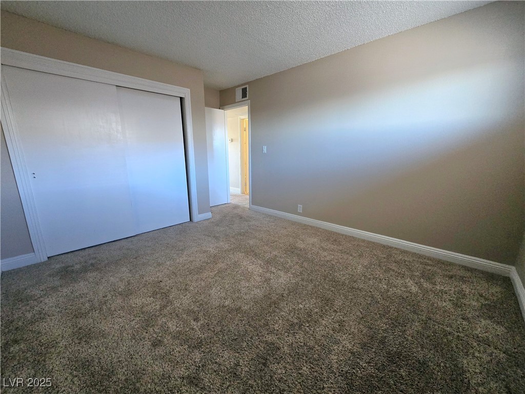 5248 Pebble Beach Boulevard, Unit D Las Vegas, NV 89108 - Photo 13 of 13 Unfurnished bedroom featuring a textured ceiling, carpet, and a closet