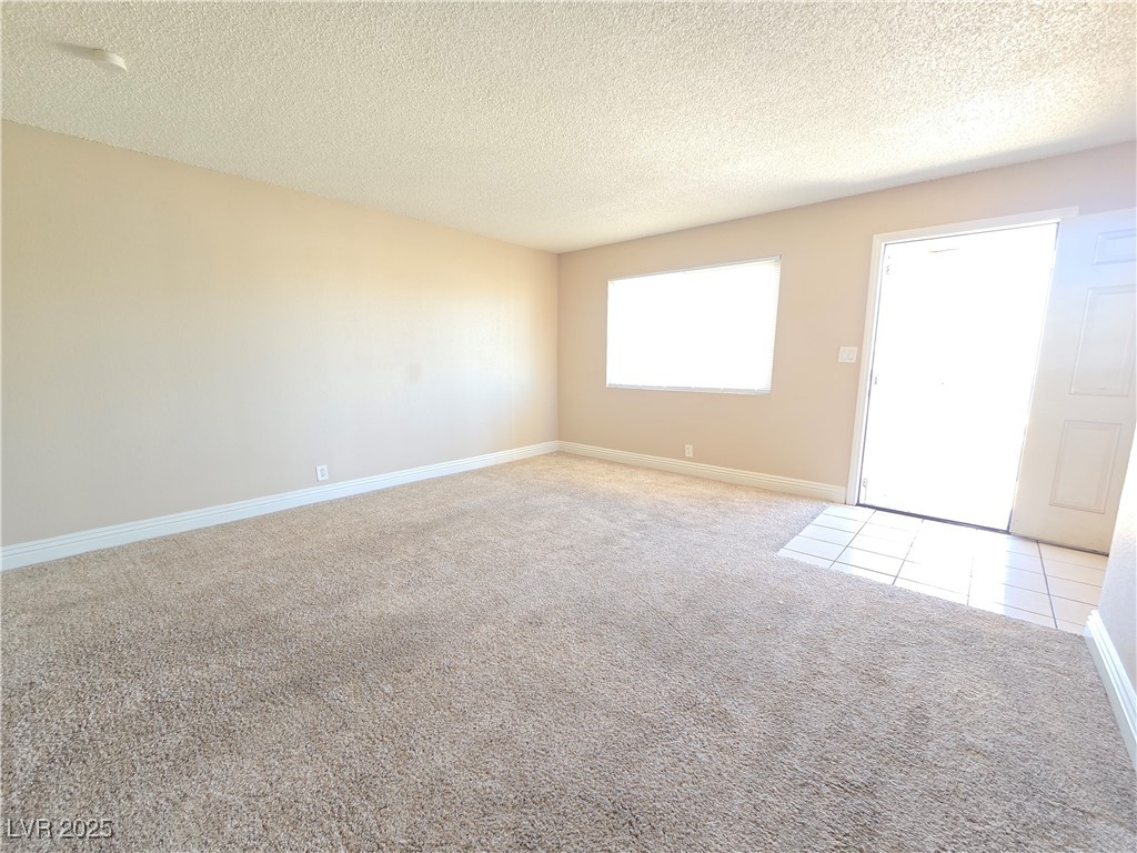 5248 Pebble Beach Boulevard, Unit D Las Vegas, NV 89108 - Photo 4 of 13 Empty room featuring a textured ceiling and light carpet