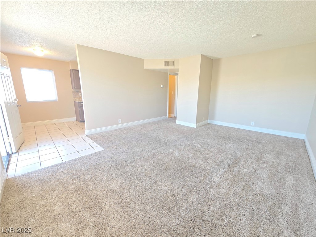 5248 Pebble Beach Boulevard, Unit D Las Vegas, NV 89108 - Photo 6 of 13 Spare room with a textured ceiling, light tile patterned flooring, and light carpet