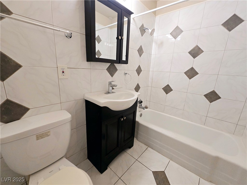 5248 Pebble Beach Boulevard, Unit D Las Vegas, NV 89108 - Photo 7 of 13 Bathroom with tile walls, vanity, shower / bathtub combination, and light tile patterned floors
