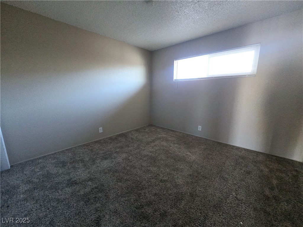 5248 Pebble Beach Boulevard, Unit D Las Vegas, NV 89108 - Photo 8 of 13 Unfurnished room featuring a textured ceiling and carpet floors