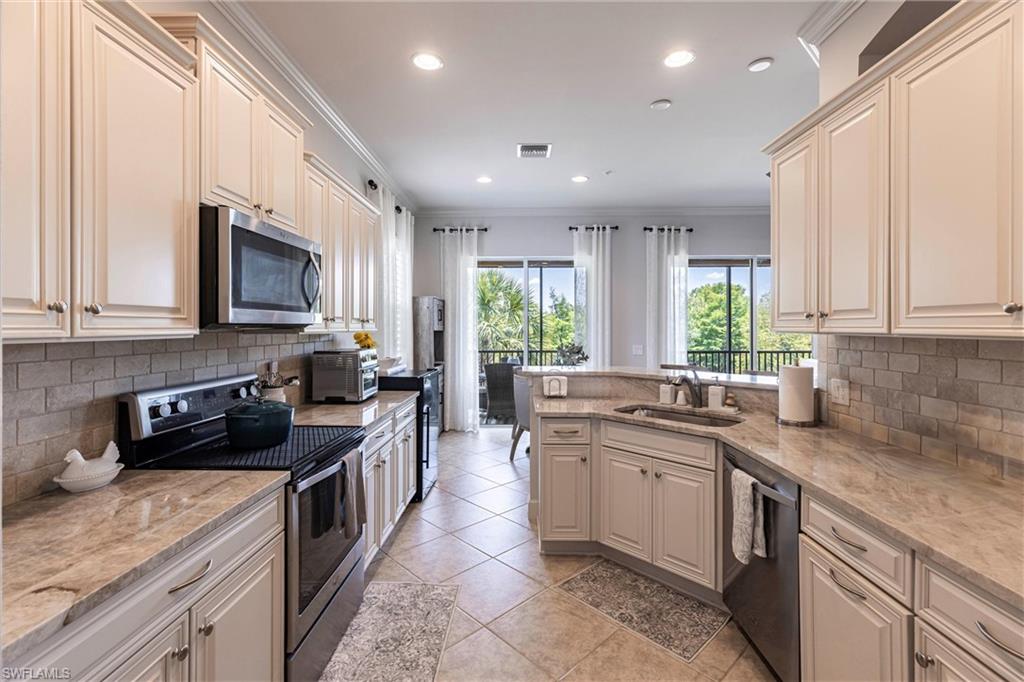 9550 Ironstone Terrace, Unit 201 Naples, FL 34120 - Photo 14 of 50 Kitchen with appliances with stainless steel finishes, a sink, crown molding, backsplash, and recessed lighting