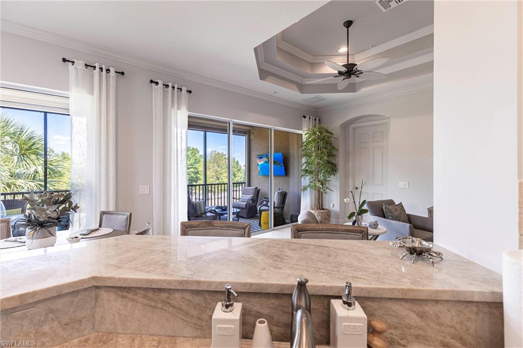 9550 Ironstone Terrace, Unit 201 Naples, FL 34120 - Photo 50 of 50 Kitchen featuring open floor plan, crown molding, light stone counters, a ceiling fan, and arched walkways
