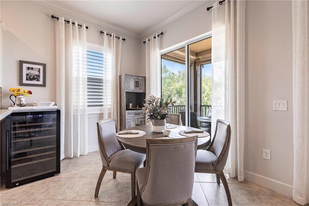 9550 Ironstone Terrace, Unit 201 Naples, FL 34120 - Photo 19 of 50 Dining space featuring wine cooler, light tile patterned flooring, baseboards, and ornamental molding