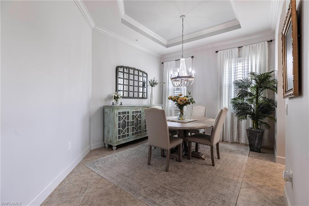 9550 Ironstone Terrace, Unit 201 Naples, FL 34120 - Photo 21 of 50 Tiled dining room featuring a chandelier, crown molding, a tray ceiling, and baseboards