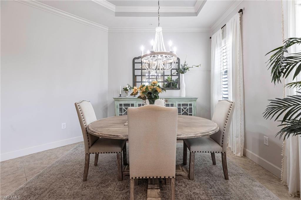 9550 Ironstone Terrace, Unit 201 Naples, FL 34120 - Photo 22 of 50 Dining area featuring a chandelier, crown molding, a tray ceiling, and baseboards