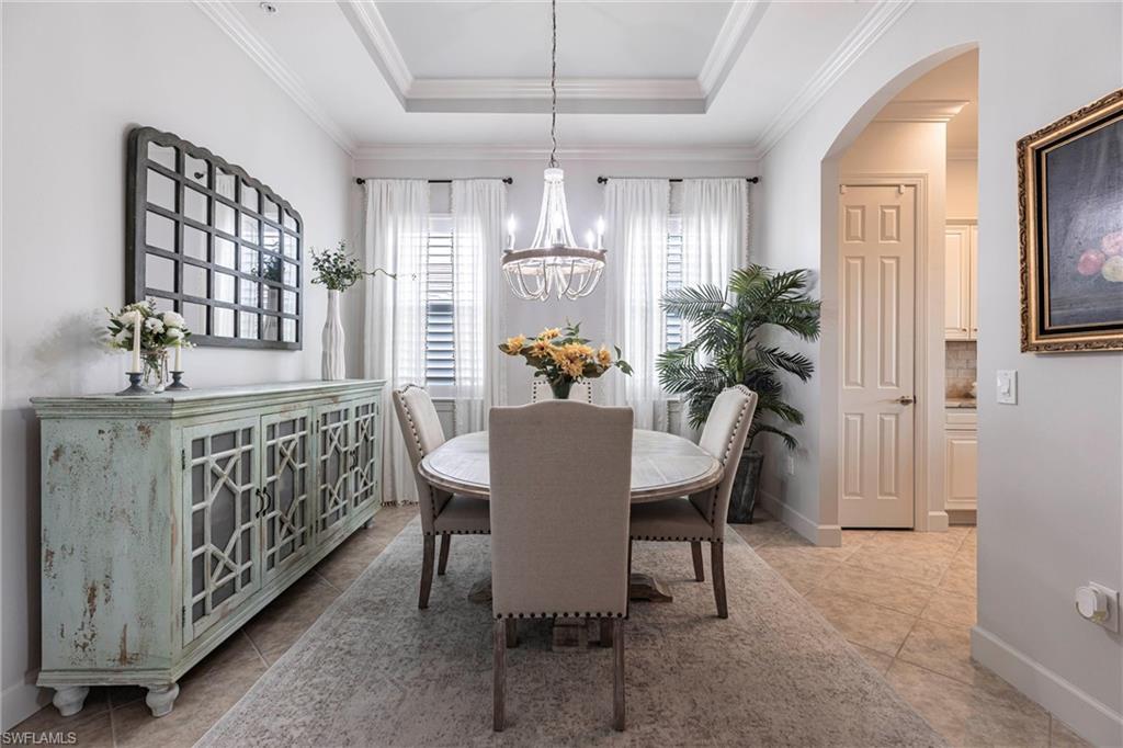 9550 Ironstone Terrace, Unit 201 Naples, FL 34120 - Photo 23 of 50 Dining area featuring a chandelier, arched walkways, ornamental molding, a raised ceiling, and tile patterned flooring