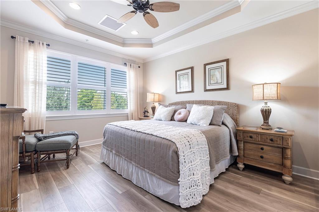 9550 Ironstone Terrace, Unit 201 Naples, FL 34120 - Photo 25 of 50 Bedroom with a raised ceiling, wood finished floors, baseboards, crown molding, and a ceiling fan