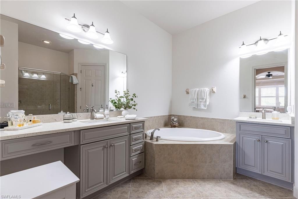 9550 Ironstone Terrace, Unit 201 Naples, FL 34120 - Photo 28 of 50 Bathroom featuring a shower stall, a garden tub, tile patterned floors, and two vanities