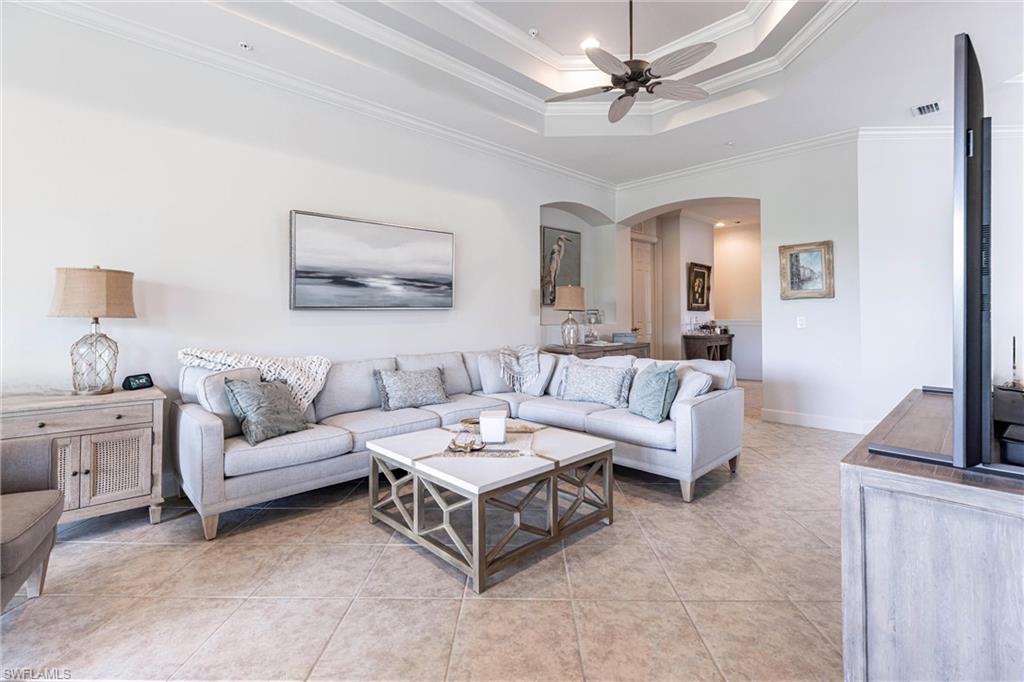 9550 Ironstone Terrace, Unit 201 Naples, FL 34120 - Photo 5 of 50 Living room featuring arched walkways, ceiling fan, crown molding, light tile patterned floors, and baseboards