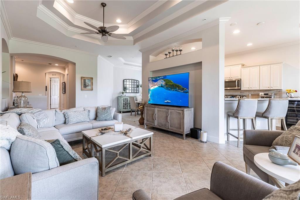 9550 Ironstone Terrace, Unit 201 Naples, FL 34120 - Photo 8 of 50 Living area with arched walkways, ceiling fan, crown molding, a tray ceiling, and light tile patterned floors