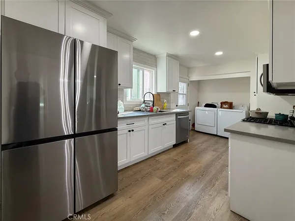 a kitchen with stainless steel appliances granite countertop a refrigerator sink and white cabinets