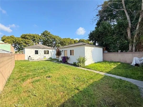 a view of a white house with a big yard and potted plants
