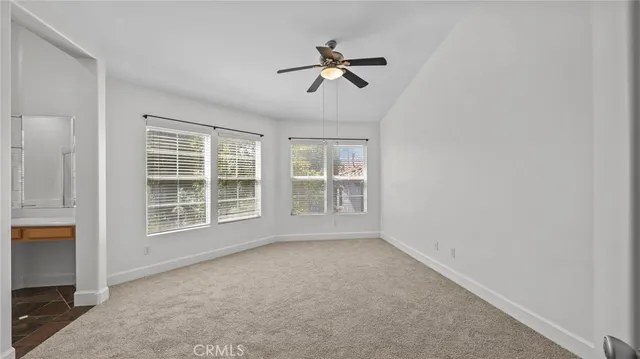 an empty room with a ceiling fan and windows