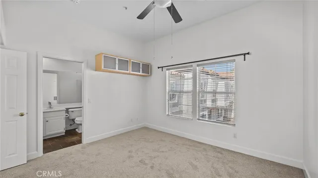an empty room with chandelier fan and windows