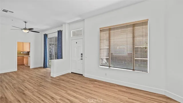 a view of an empty room with wooden floor and a window