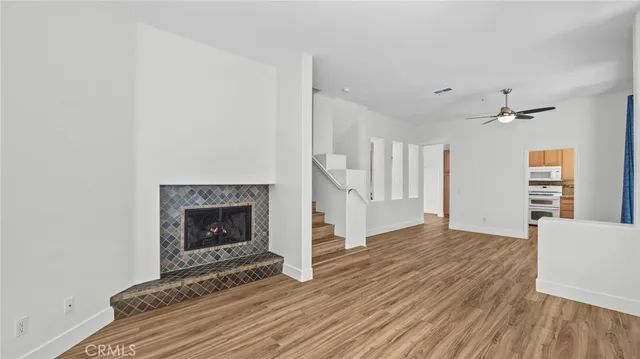 an empty room with wooden floor fireplace and windows