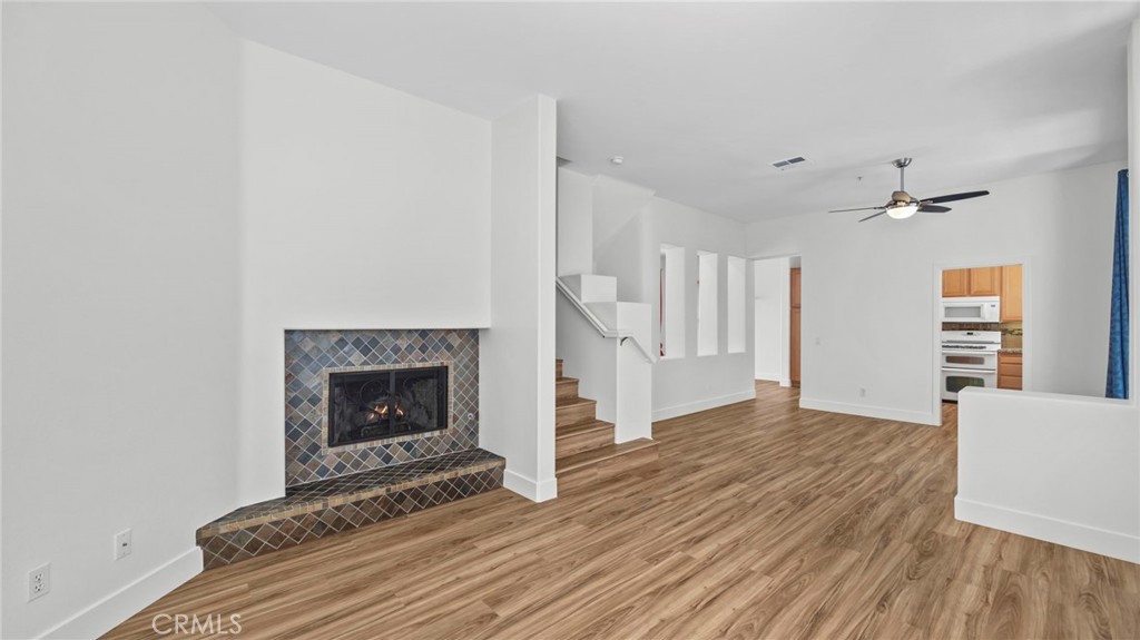 12626 Nicklaus Lane Tustin, CA 92782 - Photo 5 of 36 an empty room with wooden floor fireplace and windows