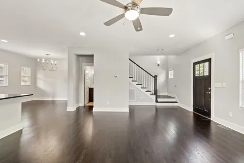 an empty room with wooden floor ceiling fan and windows