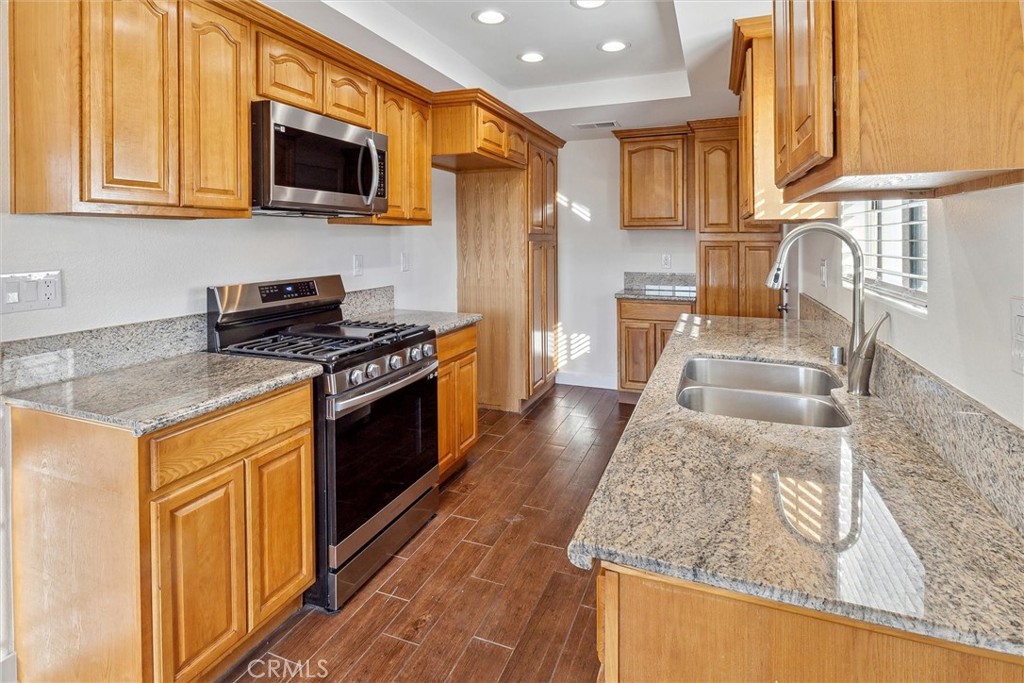5153 Loma Verde Oceanside, CA 92056 - Photo 5 of 18 a kitchen with stainless steel appliances granite countertop a stove a sink and a microwave