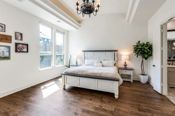 a bedroom with a large bed a chandelier and a window