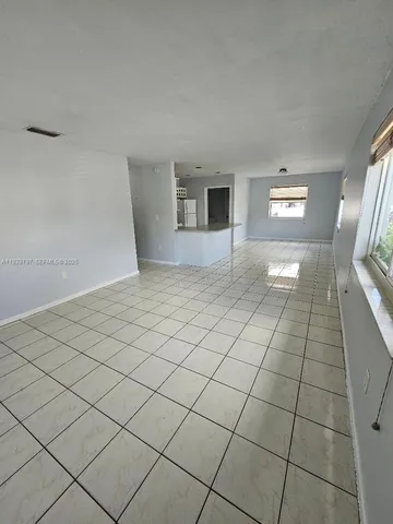 a view of an empty room with window and chandelier fan