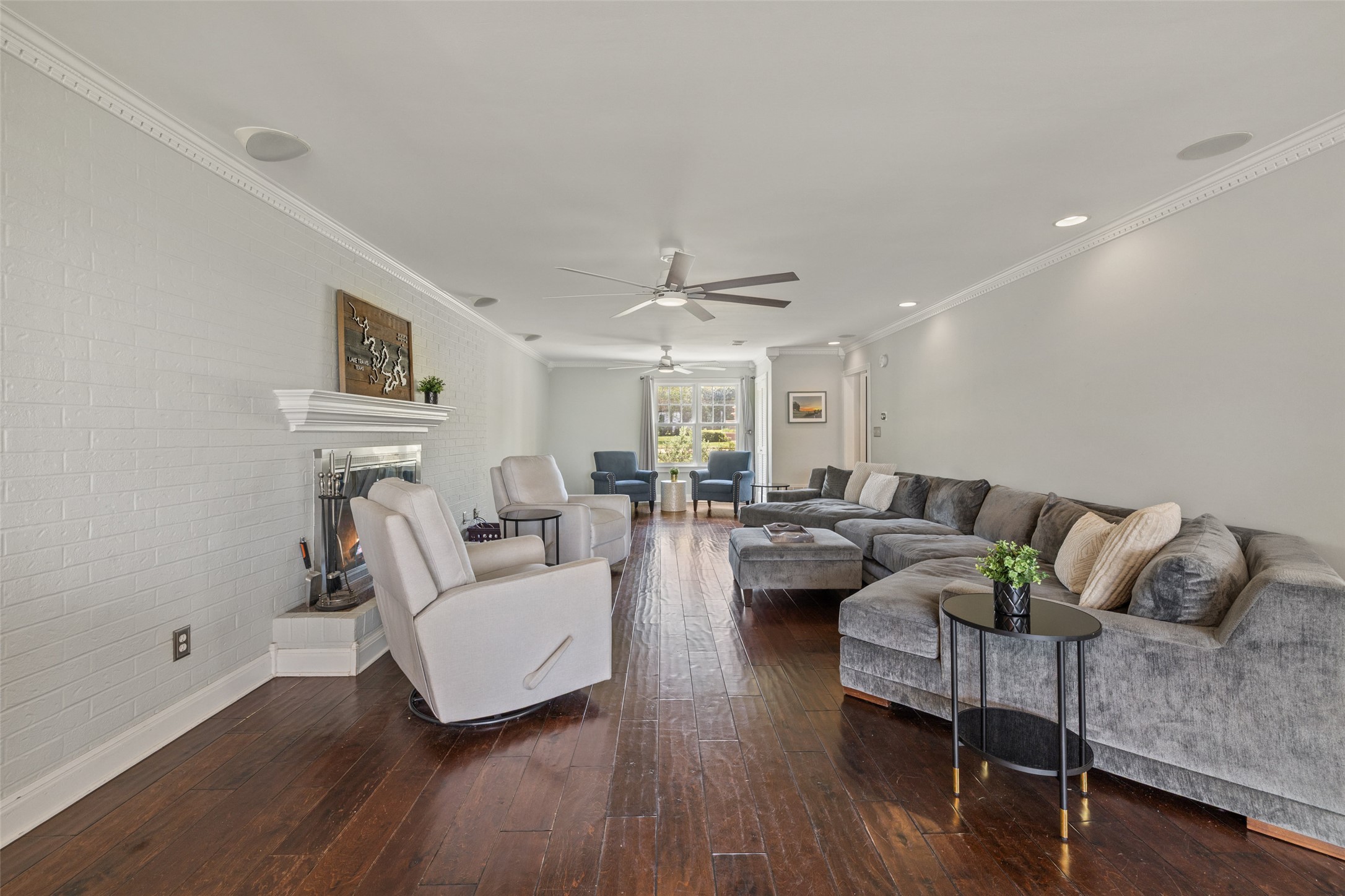 17700 North Rim Drive Leander, TX 78641 - Photo 18 of 38 Living area featuring wood-type flooring, ceiling fan, brick wall, crown molding, and a warm lit fireplace
