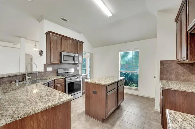 a kitchen with stainless steel appliances granite countertop a stove top oven a sink dishwasher and a refrigerator