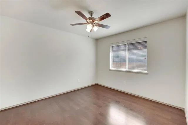 an empty room with ceiling fan and windows