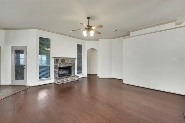 a view of an empty room with wooden floor fireplace and a window