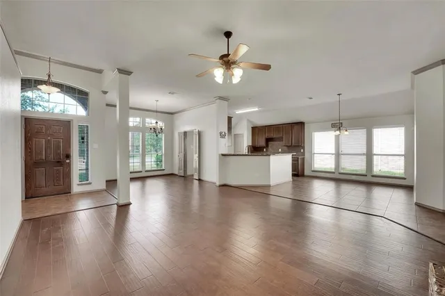 a view of a kitchen with an empty room and wooden floor