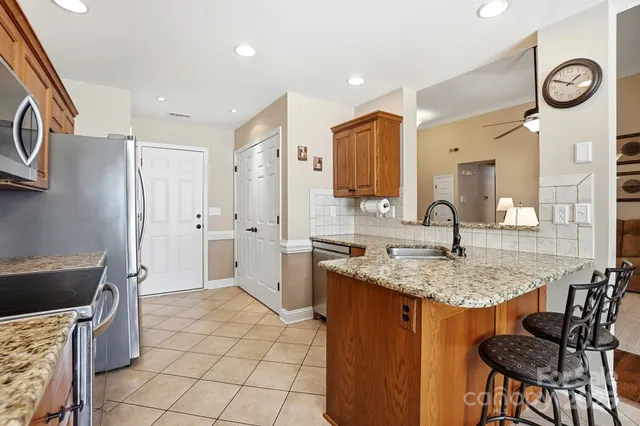 a kitchen with stainless steel appliances kitchen island granite countertop a stove top oven a sink dishwasher and a refrigerator with wooden cabinets