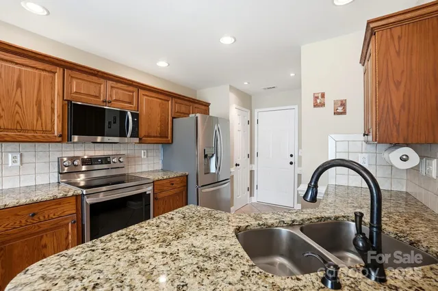 a kitchen with stainless steel appliances granite countertop a stove top oven a sink dishwasher a dining table and chairs with wooden floor