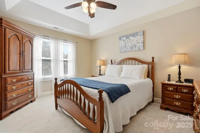 a bedroom with a bed a dresser with potted plants on dresser