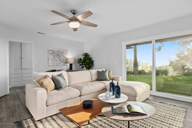 a living room with furniture and a large window with garden view