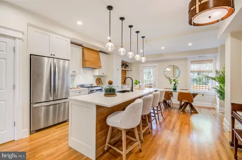 a kitchen with stainless steel appliances a dining table chairs stove and refrigerator