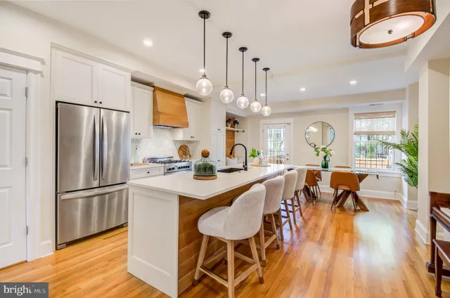 a kitchen with stainless steel appliances a dining table chairs stove and refrigerator