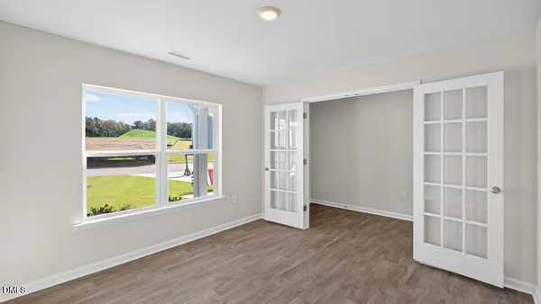 an empty room with wooden floor and windows