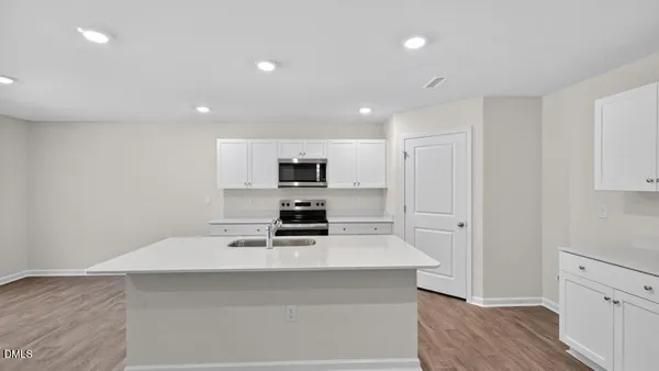 a kitchen with stainless steel appliances a sink a stove a refrigerator cabinets and a window