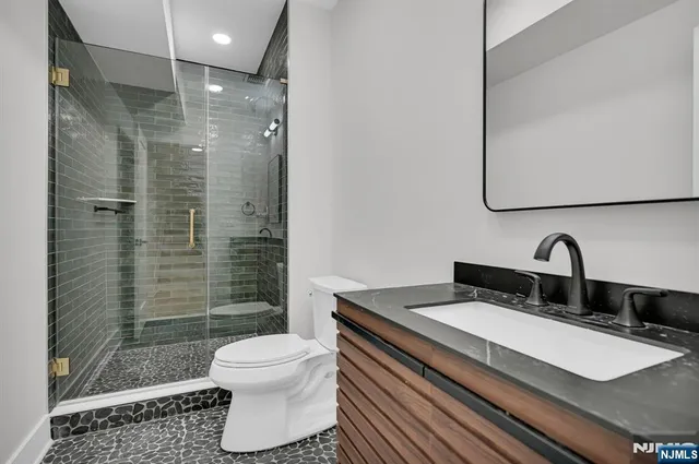 a bathroom with a sink toilet a mirror and shower